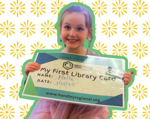 Little girl smiling with larger than life library card titled 'my first Library Card"